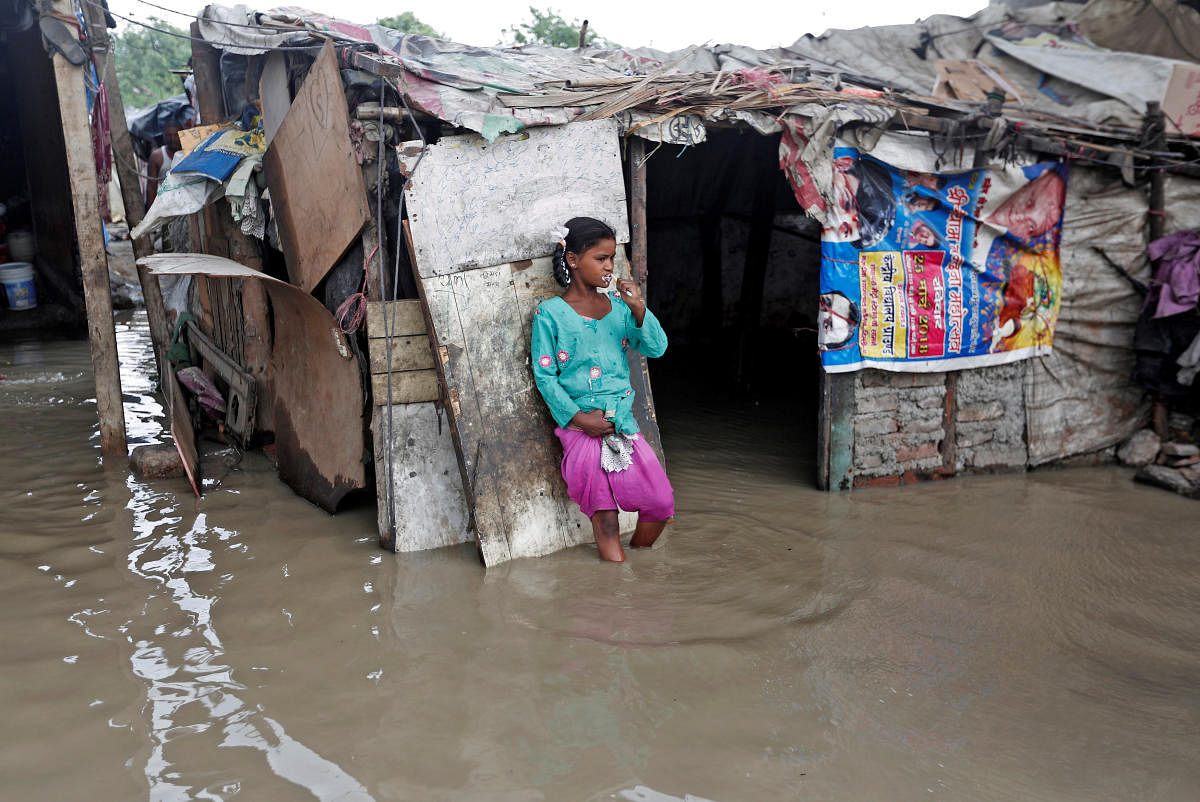 A girl brushes her teeth as she stands outside her submerged shanty at a slum area after a rise in the waters of the river Yamuna. (Reuters)