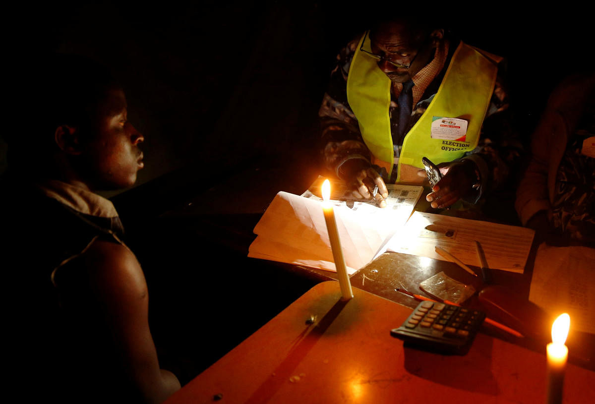 An election official assists a voter during the country's general elections in Chegutu. Reuters
