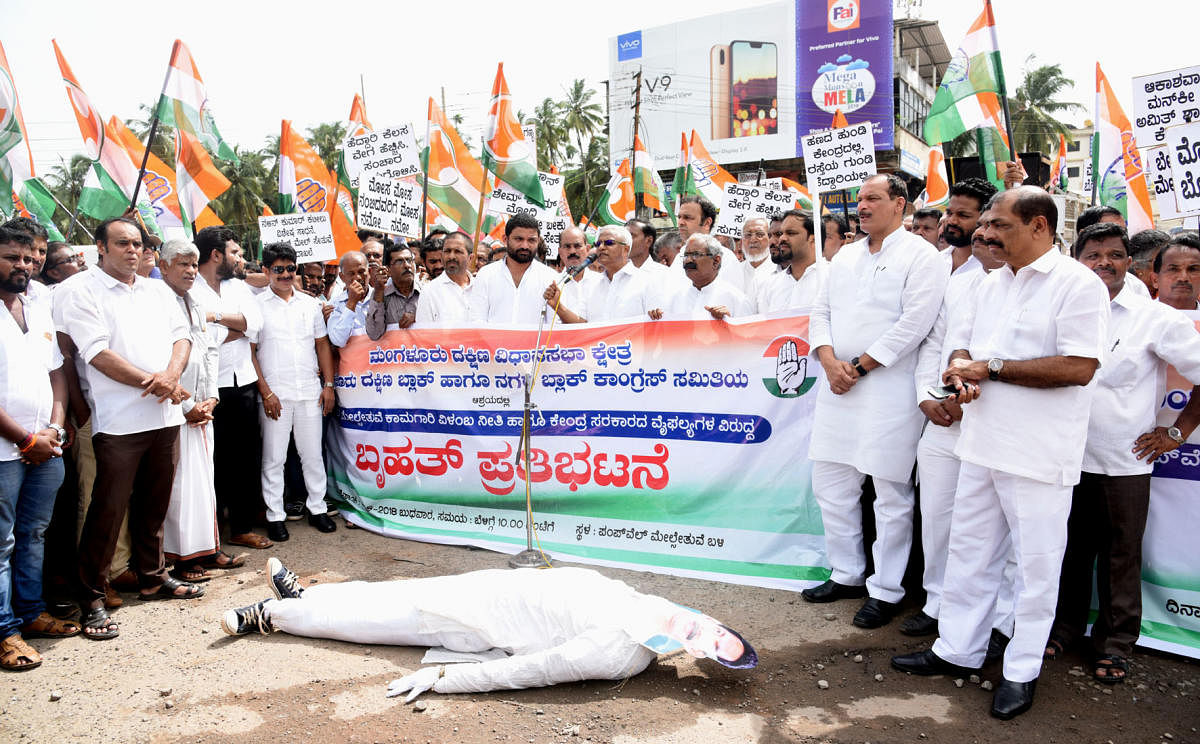 Congress workers stage a protest at Pumpwell Circle in Mangaluru on Wednesday against the delay in the work of flyovers and poor condition of the national highway.
