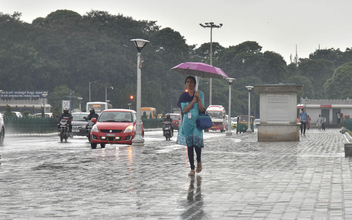 A woman walks with a umbrella during a sudden downpour near Vidhana Soudha, in Bengaluru. (DH File Photo/Janardhan B K)