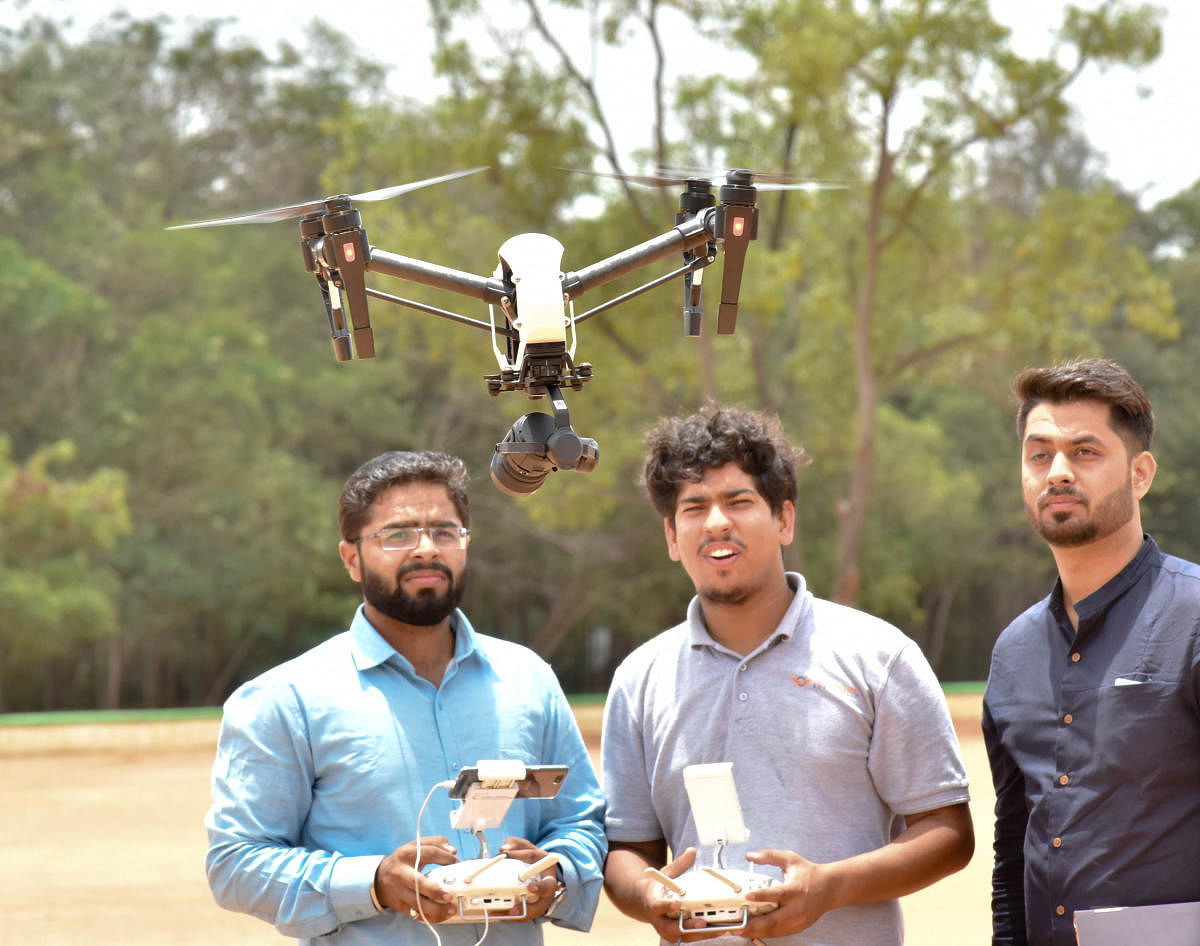 Volunteers operate a drone camera at the launch of Drone applications for Agriculture activities at GKVK in Bengaluru on Thursday. DH Photo/Janardhan B K
