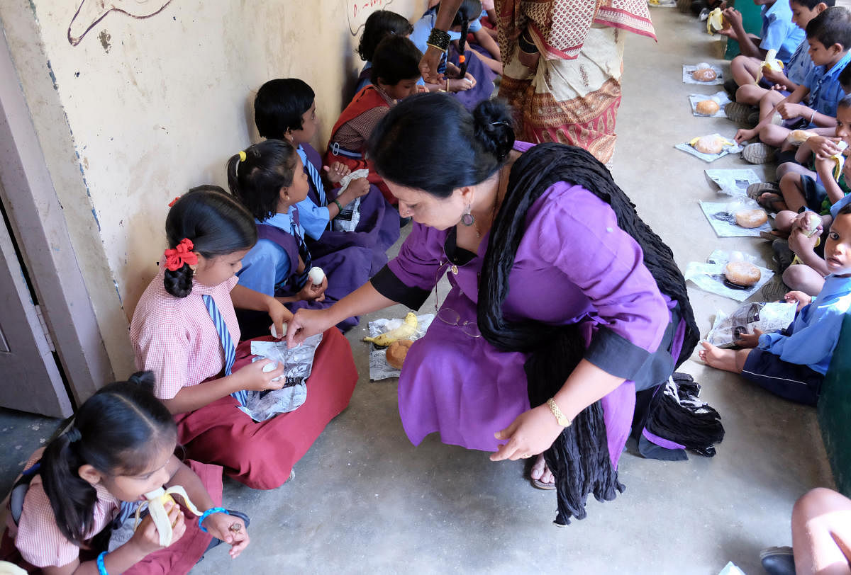 Sarala Menon, former president, Inner Wheel Club of Bangalore IT Corridor (IWCBITC), distributing food to children of the Government Lower Primary School at Pattandur Agrahara, Whitefield, on Thursday. DH Photo/Grace Hauck