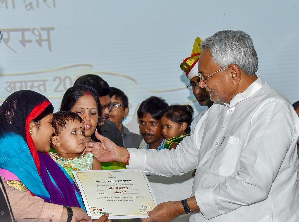 Bihar Chief Minister Nitish Kumar gives away a cheque and a certificate to a beneficiary during "Mukhyamantri Kanya Utthan Yojana" (Girls Empowerment Scheme), at Adhiveshan Bhawan in Patna on Friday. (PTI Photo)