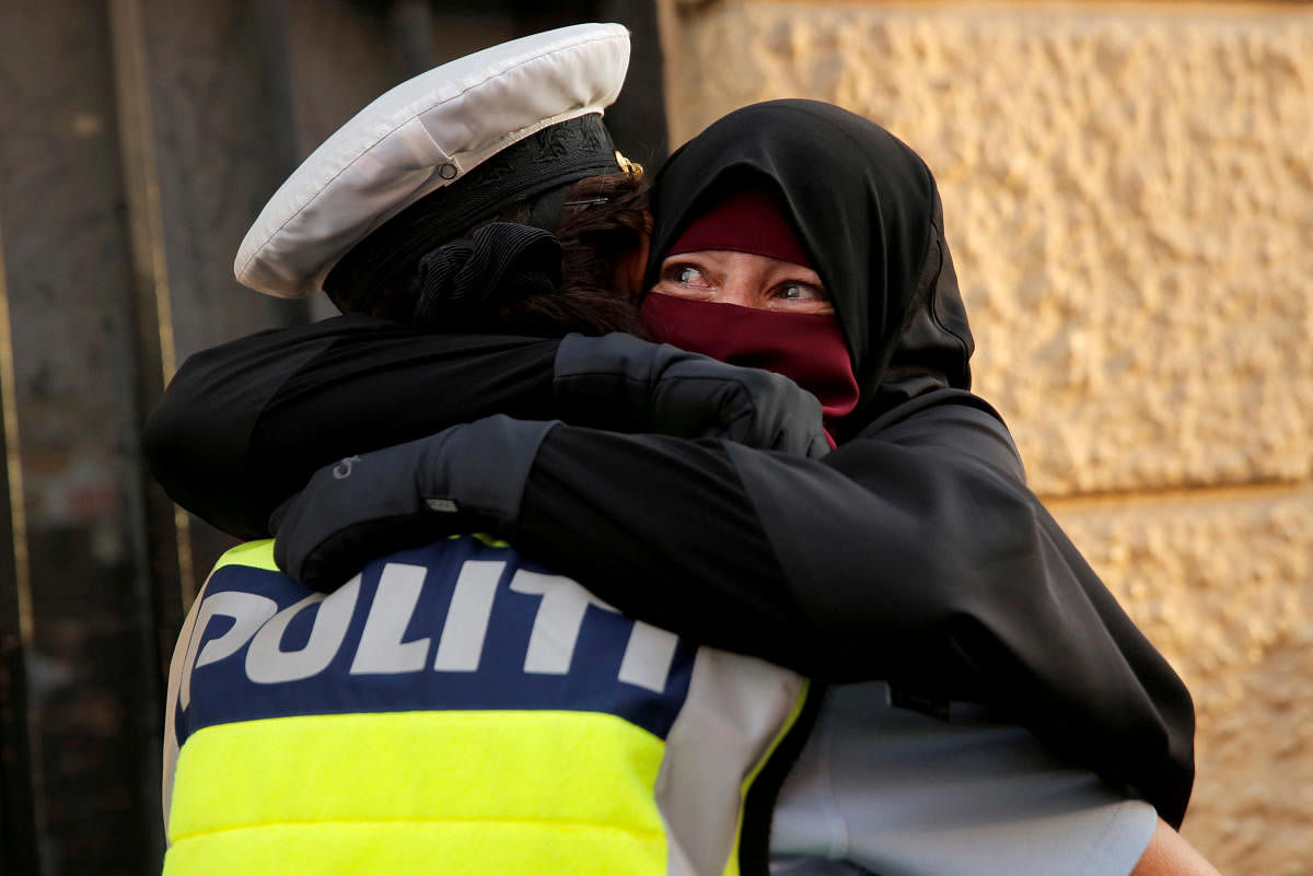 Ayah, 37, a wearer of the niqab weeps as she is embraced by a police officer during a demonstration against the Danish face veil ban in Copenhagen, Denmark, August 1, 2018. (REUTERS/Andrew Kelly)
