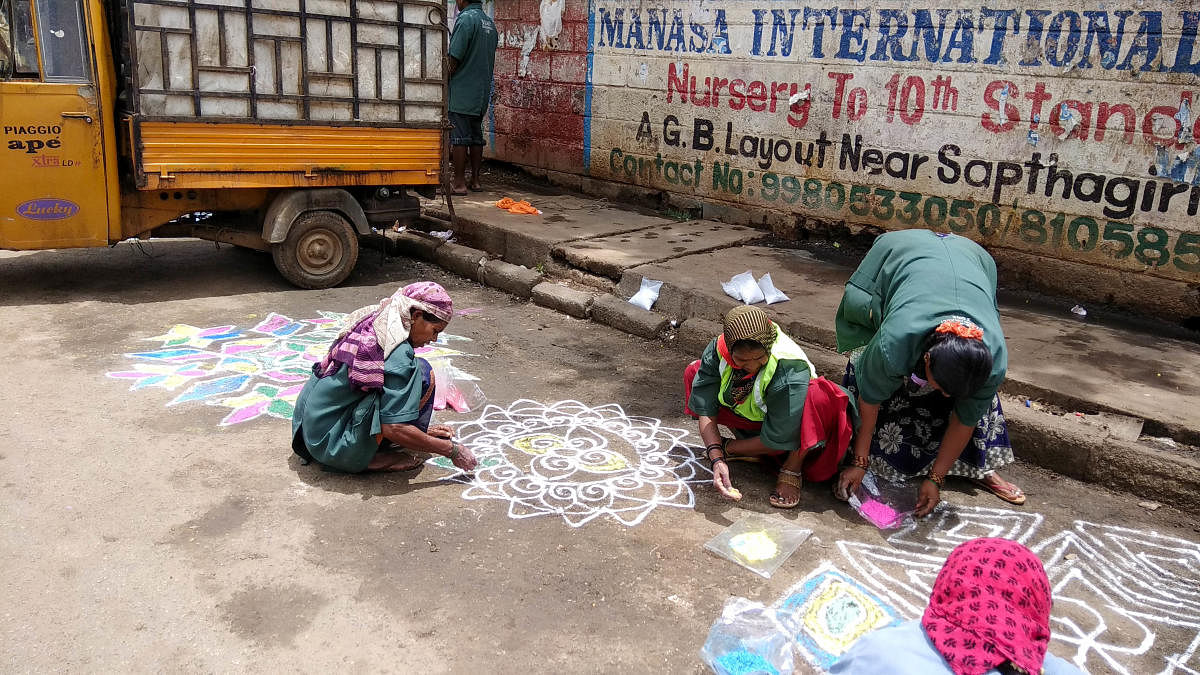 Municipal workers create rangoli artworks on a garbage black spot in Defence Colony near Bagalagunte, Hesaraghatta Main Road, on Friday. DH PHOTO/B H Shivakumar