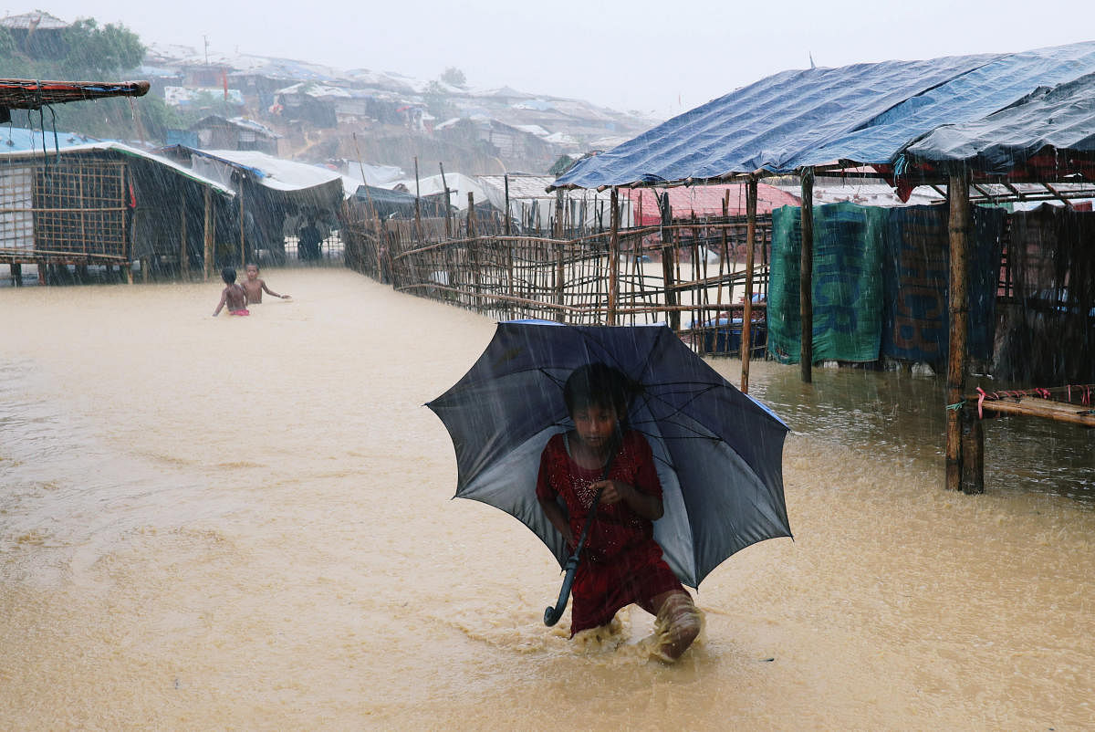 A Rohingya refugee girl walks along the water with umbrella as parts of the Kutupalong camp is flooded during heavy rain in Cox's Bazar, Bangladesh. (Reuters File Photo)