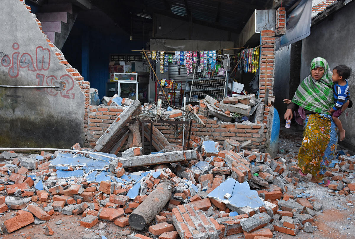 A woman walks past debris from a collapsed wall following a strong earthquake in Lendang Bajur Hamlet, Lombok island, indonesia August 6, 2018 in this photo taken by Antara Foto. Antara Foto/Ahmad Subaidi/ via REUTERS.