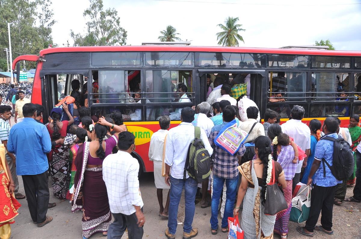 People board a city bus in Hosapete as private vehicles.