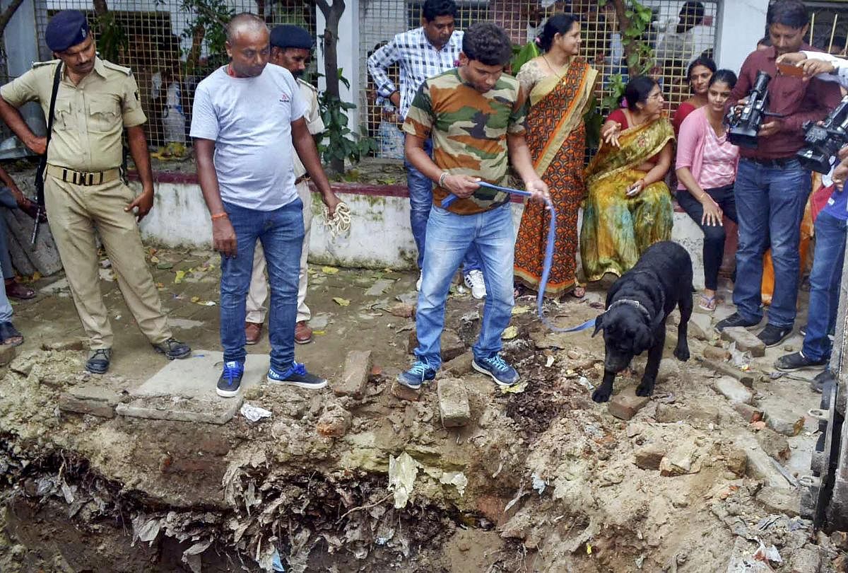 Muzaffarpur: Police with their sniffer dogs investigate the site where a rape victim was allegedly buried, at a government shelter home in Muzaffarpur, on Monday, July 23, 2018. A girl of the home has alleged that one of her fellow inmates was beaten to d