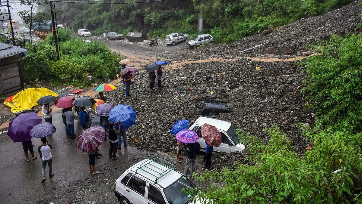 People try to retrieve vehicles from under the debris of a landslide following heavy rainfall in Shimla on Monday. (PTI Photo)