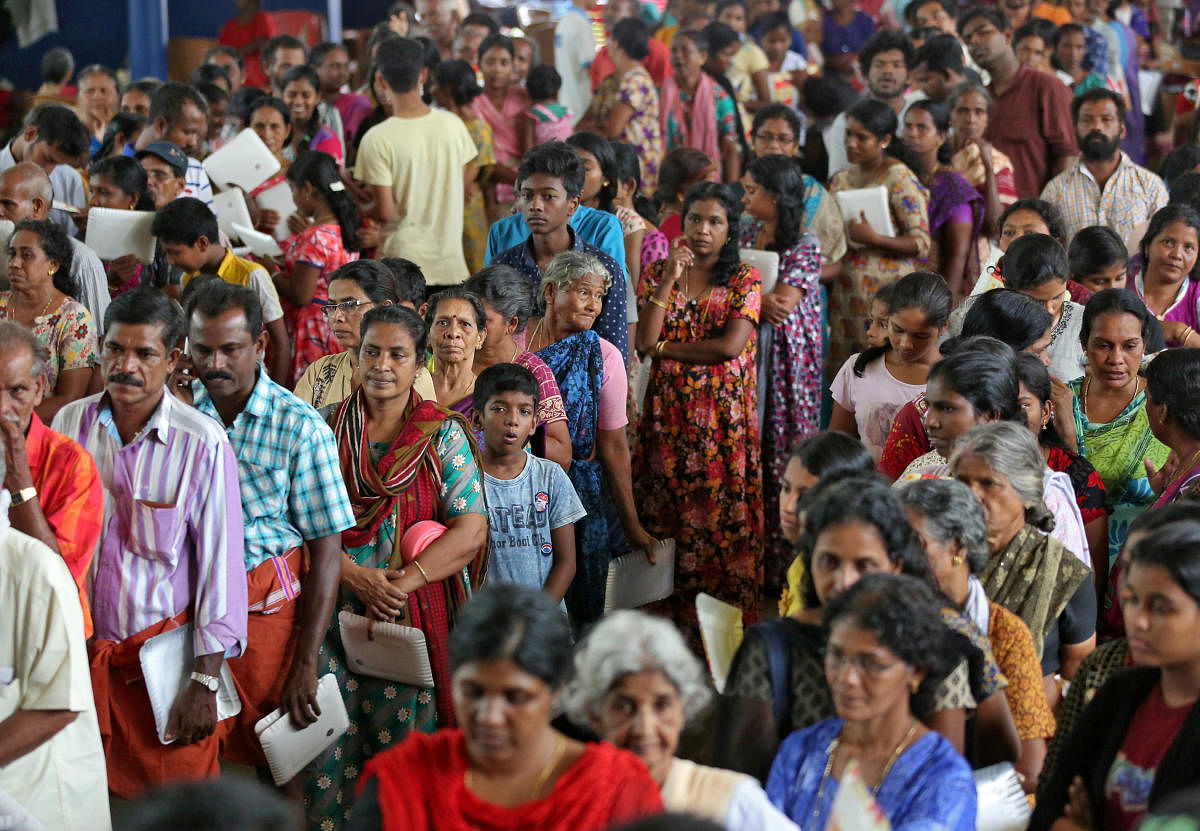 Flood-affected people wait to receive food inside a college auditorium, which has been converted into a temporary relief camp, in Kochi. Reuters photo
