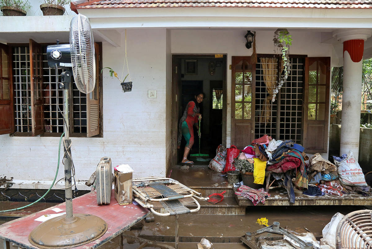 A woman cleans the mud from the entrance of her house following floods in Paravur in Kerala. Reuters