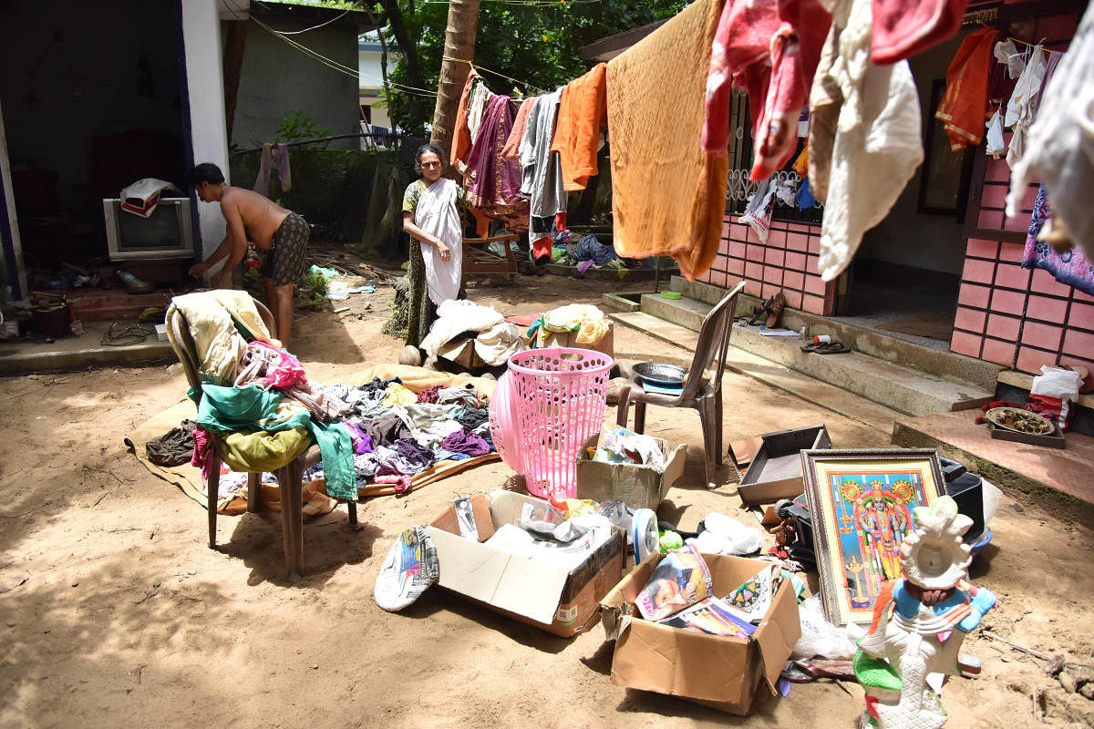 The family dries out clothes and other things outside their house after flood water receded at Purathuru in Kerala on Tuesday. DH Photo by Janardhan B K