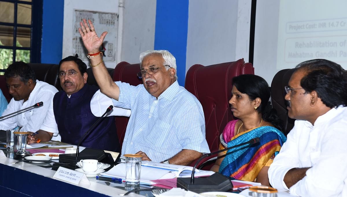 District In-charge Minister R V Deshpande speaks at 'Smart City' project progress review meeting held in Hubballi on Monday. MP Pralhad Joshi, DC Deepa Cholan, and others are present.