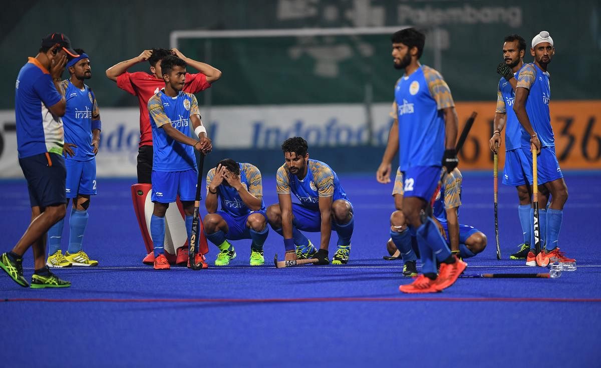 PICTURE SAYS IT ALL: Indian hockey team players and coach Harendra Singh (left) wear a dejected look after their semifinal loss to Malaysia in Jakarta on Thursday. AFP