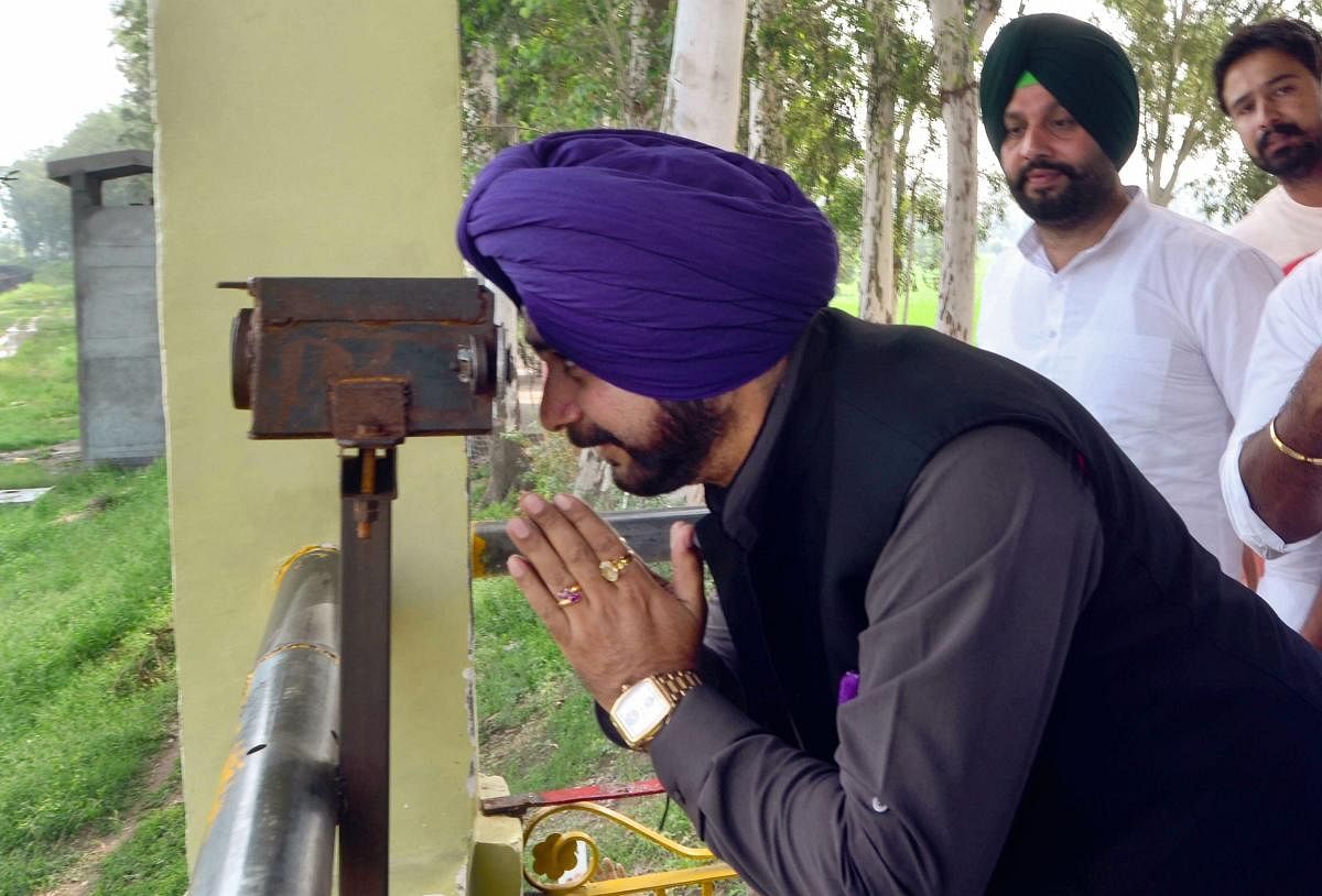Punjab Local Bodies Minister Navjot Singh Sidhu pay obeisance while seeing Gurdwara Kartarpur Sahib, located in Pakistan, through a binocular from the Indo-Pak border in Gurdaspur district on Saturday, August 25, 2018. (PTI Photo)
