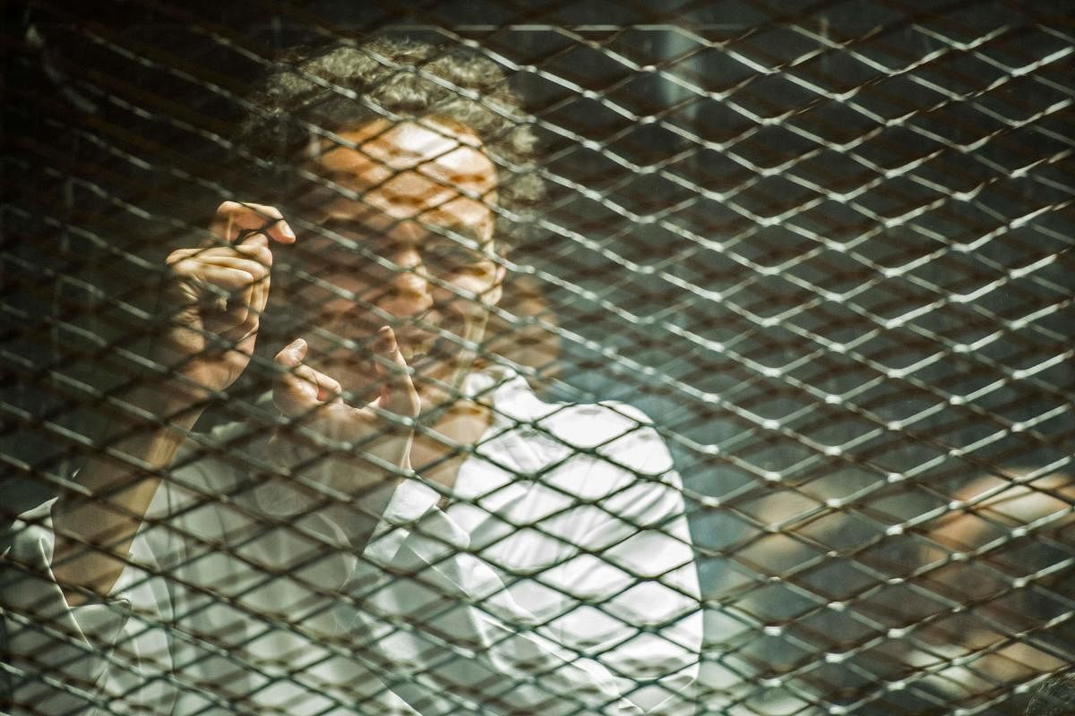 Egyptian photojournalist Mahmoud Abu Zeid, widely known as Shawkan, mimes a photographer inside a soundproof glass dock during his trial in the capital Cairo, on September 8, 2018. AFP