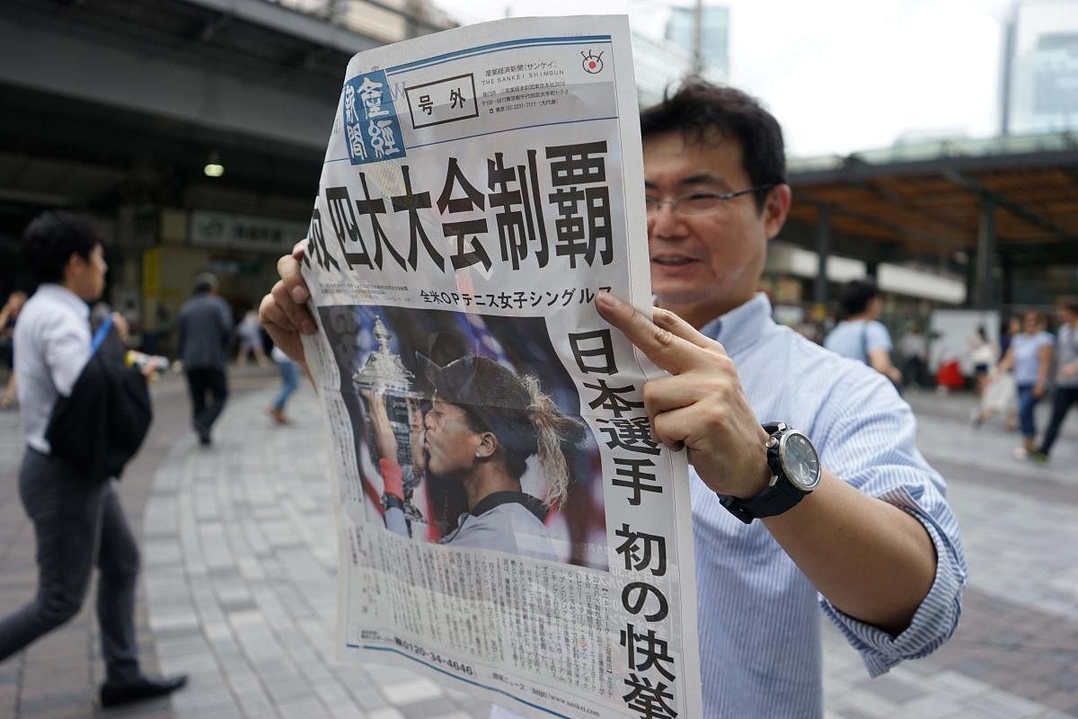 GROUND BREAKING A pedestrian reads an extra edition of a Japanese newspaper which has the report of Naomi Osaka's triumph over Serena Williams in the US Open final. AFP