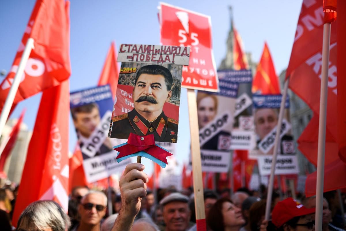 Russian Communist party supporters carry red flags and the portrait of former Soviet leader Josef Stalin as they take part in a rally against the government's proposed reform hiking the pension age in Moscow on September 2, 2018. - The draft law calls for the pension age to be gradually raised to 60 for women and 65 for men, up from the current Soviet-era norms of 55 for women and 60 for men. AFP