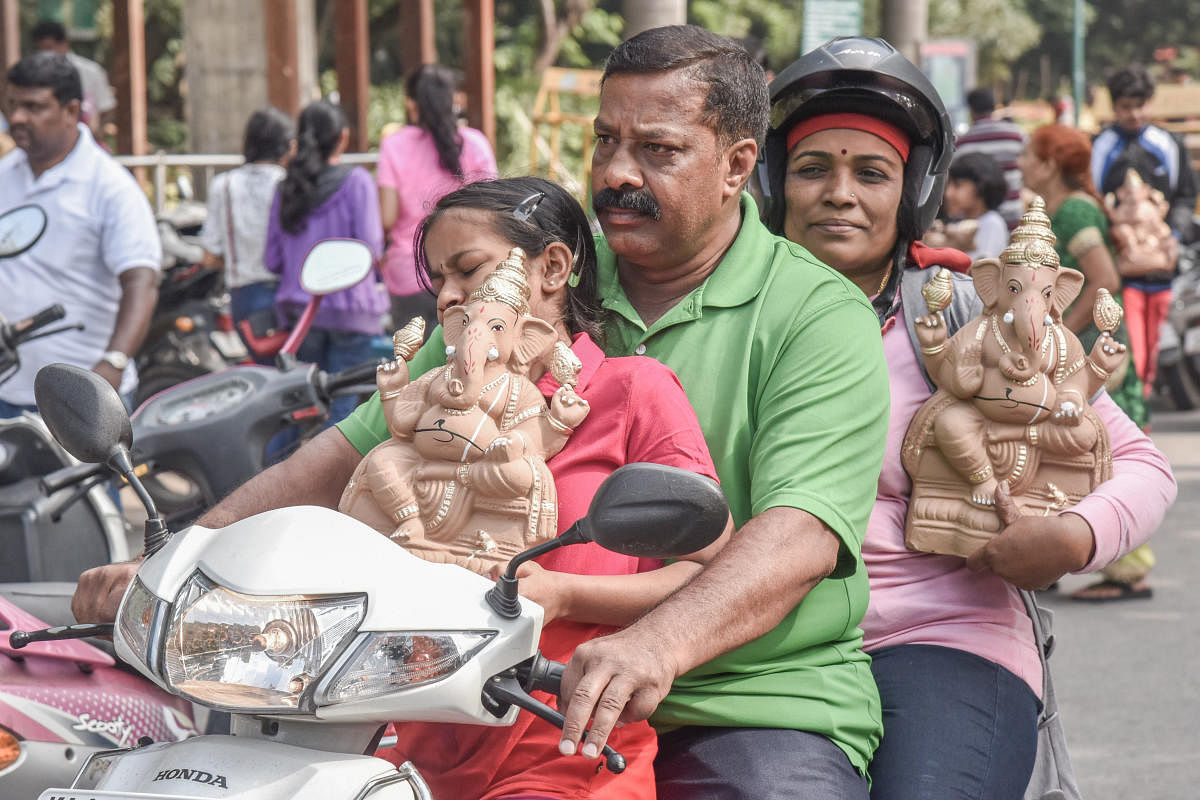 People take home clay Ganesha idols that were distributed by Mayor R Sampath Raj at an awareness programme in Cubbon Park on Sunday. DH Photo/S K Dinesh