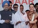 Prime Minister Manmohan Singh along with UPA Chairperson Sonia Gandhi distributes the Unique Identification (UID) project cards to a tribal woman in Tembhali, Maharashtra, on Wednesday. PTI