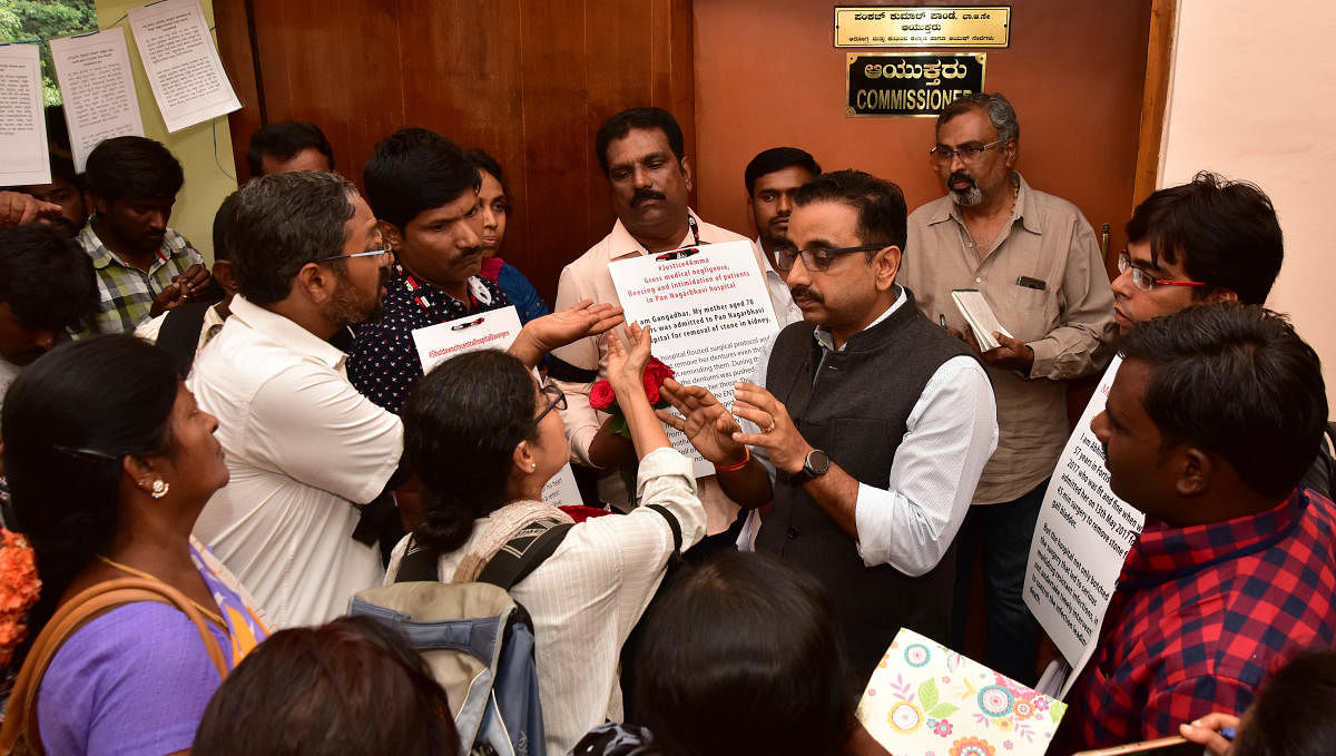 Relatives of patients misdiagnosed by doctors present roses to Pankaj Kumar Pandey, Commissioner, Health and Family Welfare, for the delay in enforcing the KPME Act in Bengaluru on Saturday. (DH PHOTO/RANJU P)