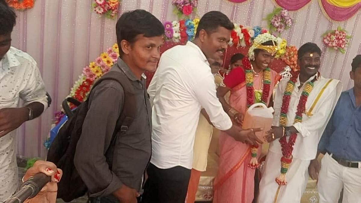 Ilanchezhian and Kanimozhi, newly wed couple, accepting 'costliest gift' of 5 litres of petrol from their friends on Sunday. DH Photo