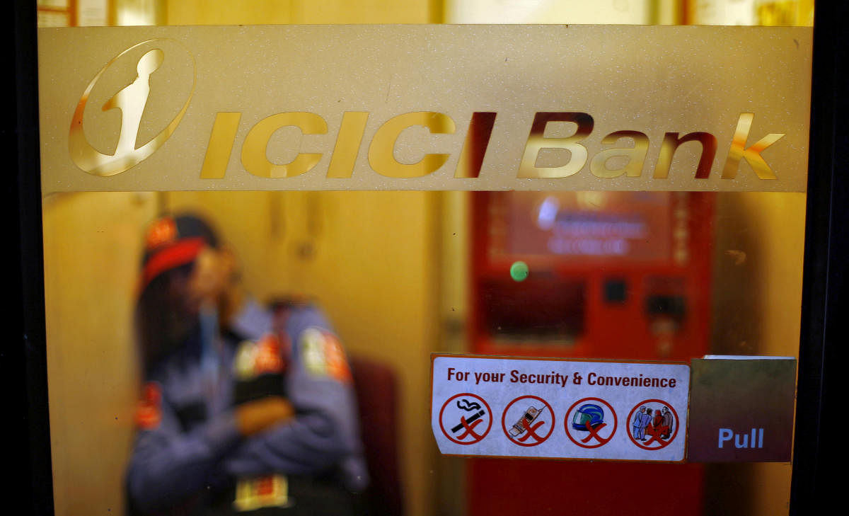 FILE PHOTO: A private security guard sleeps inside an automated teller machine (ATM) booth of ICICI bank in New Delhi. Reuters