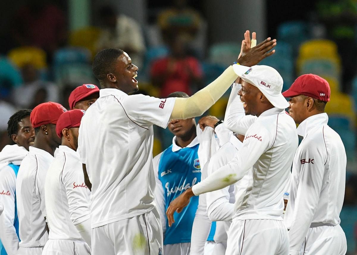 West Indies' skipper Jason Holder (left) and Roston Chase celebrate the dismissal of Danushka Gunathilaka of Sri Lanka on the second day of the third Test at Bridgetown, Barbados, on Sunday. AFP