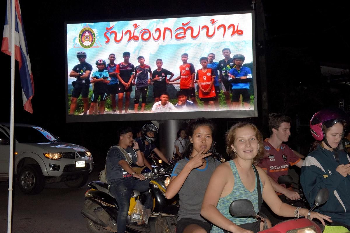 Motorists pass a billboard with a photograph showing members of the Thai children's football team "Wild Boar" and their coach with a message "welcome home brothers" displayed in Chiang Rai. AFP