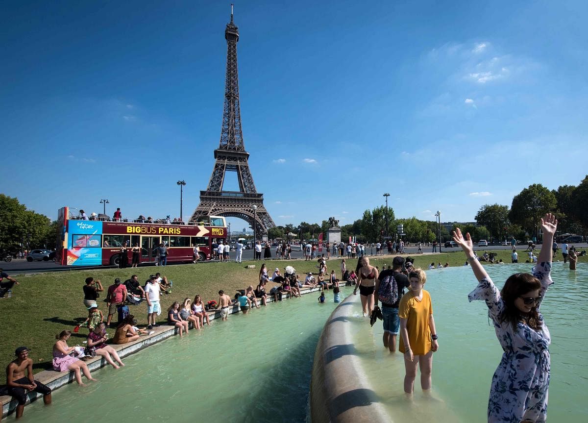 People cool themselves at the Trocadero Fountain in front of The Eiffel Tower in Paris on August 2, 2018, as a heatwave continues across Europe. / AFP PHOTO / GERARD JULIEN