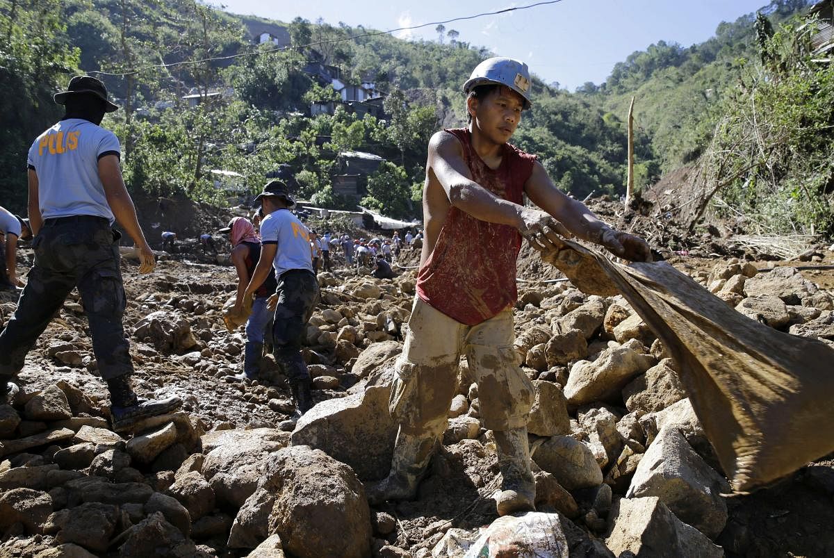 A Filipino miner, right, joins search operations at the site where victims are believed to have been buried by a landslide triggered by Typhoon Mangkhut as it lashed across Itogon, Benguet province, northern Philippines, Tuesday, Sept. 18, 2018. (AP/PTI P