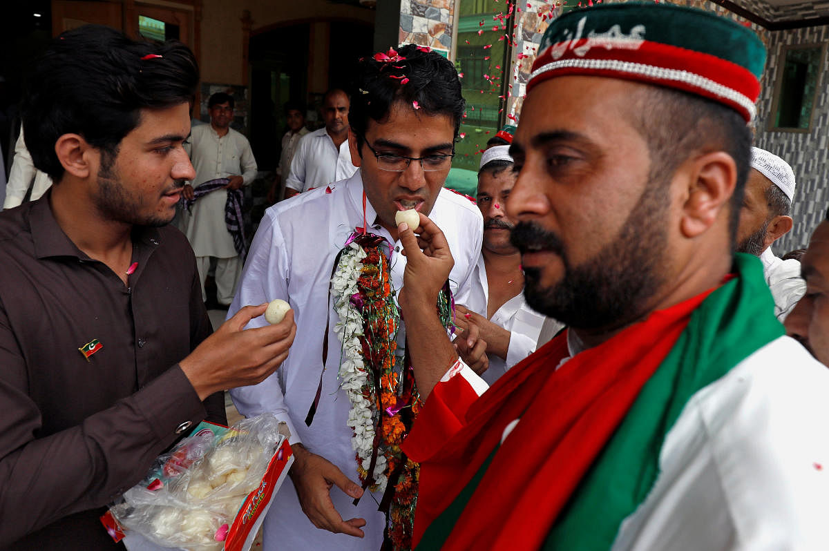 Supporters of Imran Khan, chairman of the Pakistan Tehreek-e-Insaf (PTI) party, offer sweets to each other as they celebrate a day after the general election, in Peshawar, Pakistan on Thursday. (REUTERS/Fayaz Aziz)