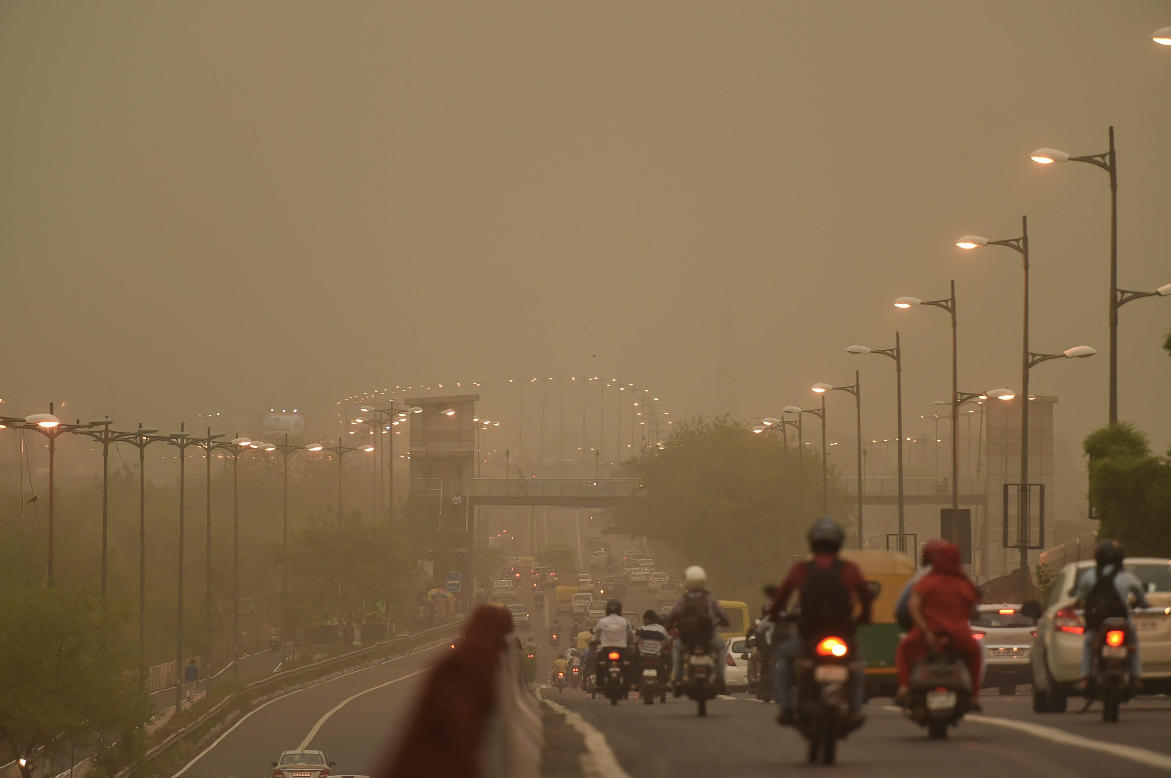 Vehicles ply slowly on a road as the weather turns hazy, in New Delhi on Tuesday. PTI