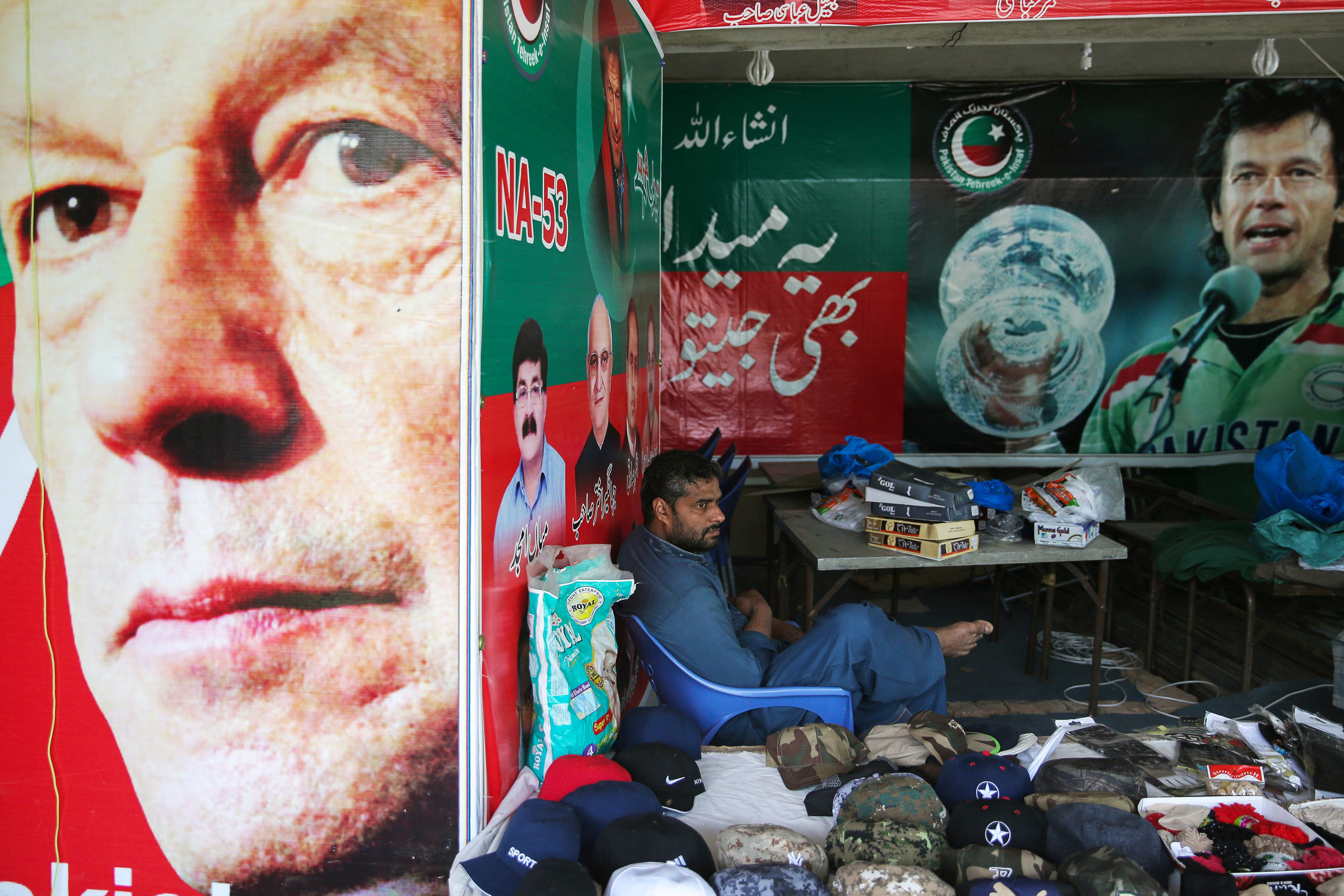 A vendor sits next to images of cricket star-turned-politician Imran Khan, chairman of Pakistan Tehreek-e-Insaf (PTI) at a market in Islamabad, Pakistan. REUTERS/Athit Perawongmetha
