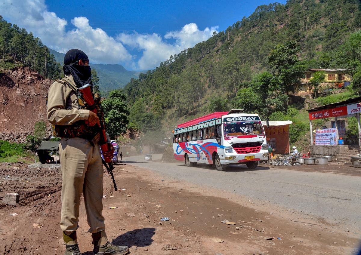 Security personnel stand guard as a bus full of pilgrims moves towards the holy cave shrine of Amarnath in the Pahalgam district of Jammu and Kashmir on July 2, 2018. (PTI File Photo)