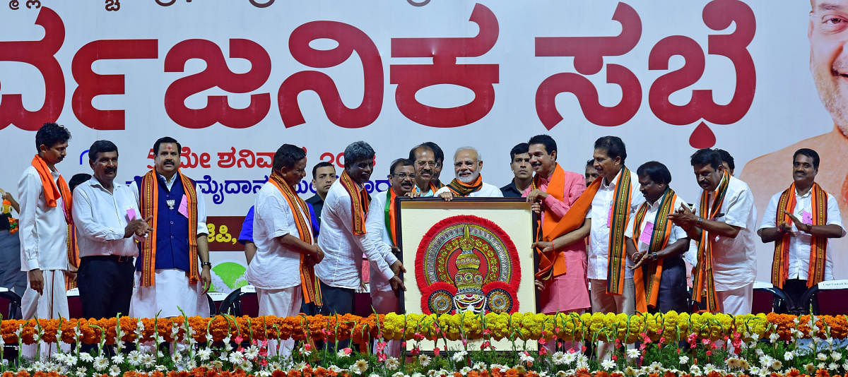 BJP leaders felicitate Narendra Modi with a Thenkuthittu Yakshagana headgear, made by Mahalasa Art School student Soumya, during the public rally at Nehru Maidan in Mangaluru on Saturday.