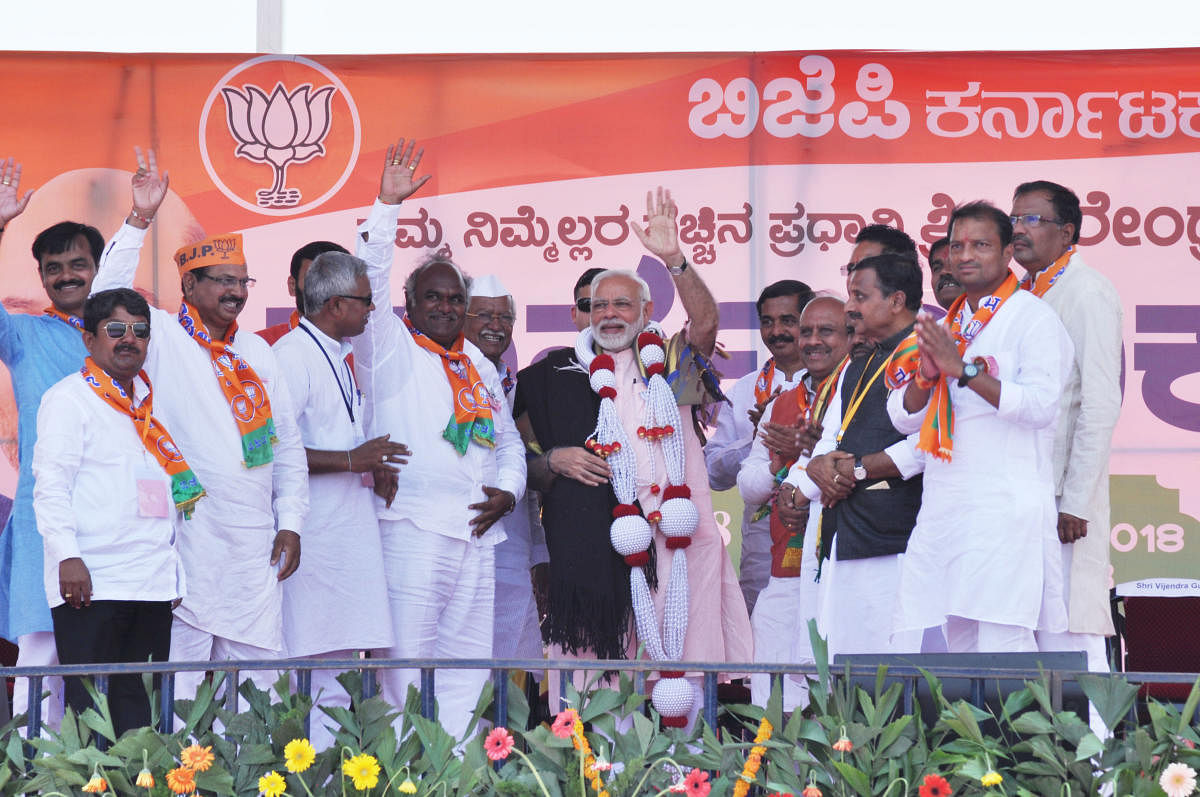 Prime Minister Narendra Modi is felicitated by presenting him a blanket during an election rally in Saravada village of Vijayapura taluk on Tuesday. DH Photo