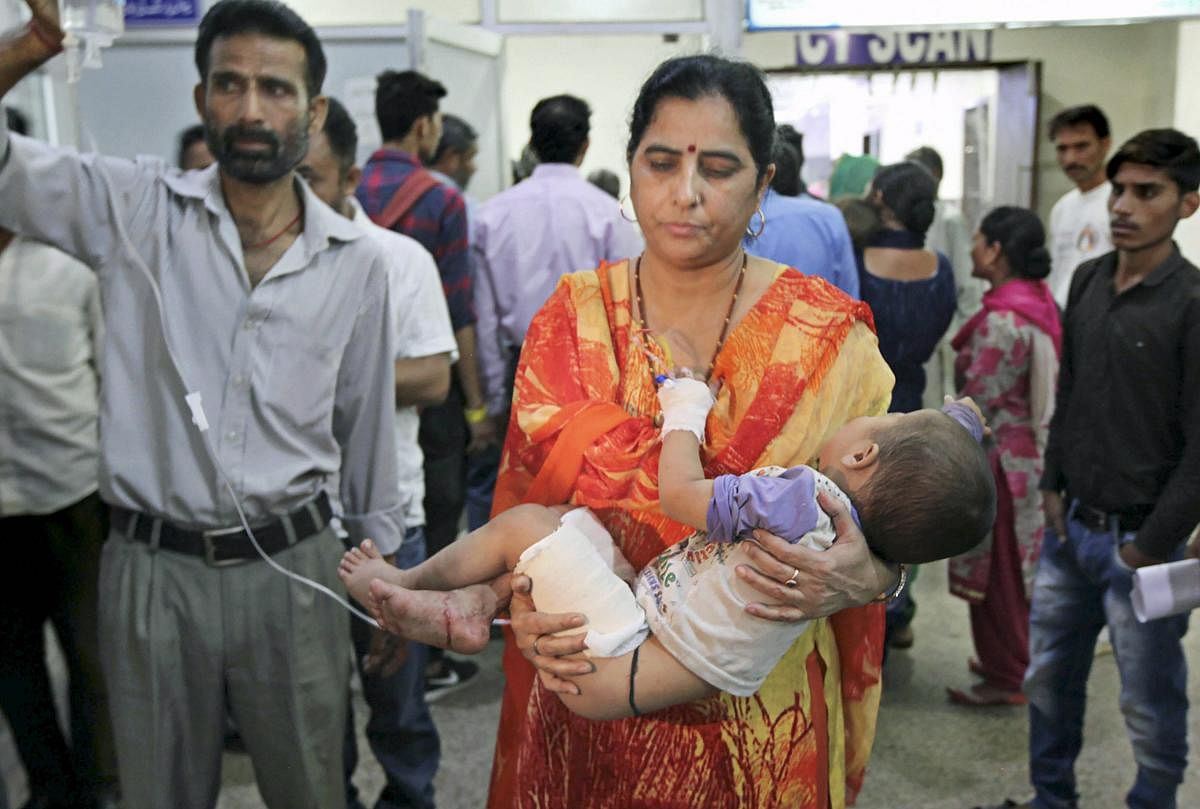 A woman carries her son, who was injured in cross-border firing, to a hospital in Jammu on Wednesday. PTI
