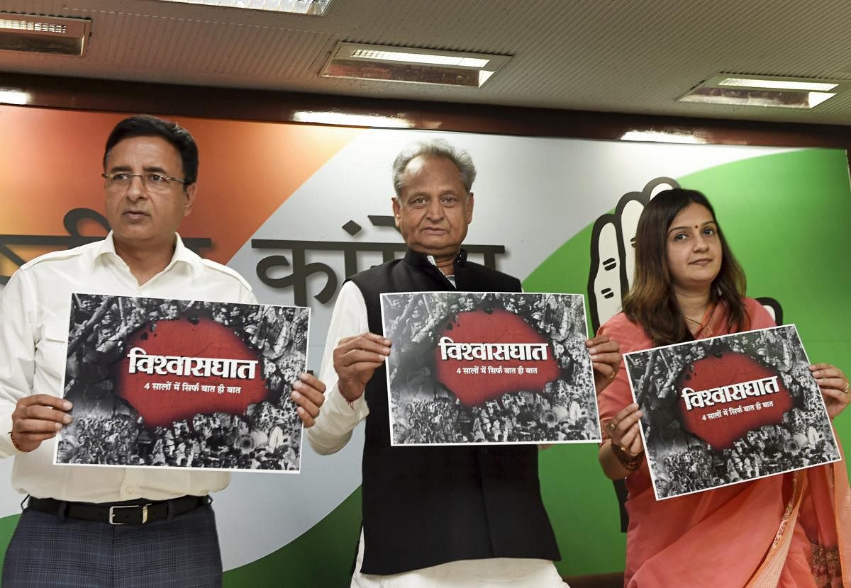 Senior Congress leader Ashok Gehlot with AICC spokespersons Randeep Singh Surjewala and Priyanka Chaturvedi release a poster before a press conference, in New Delhi, on Wednesday. PTI