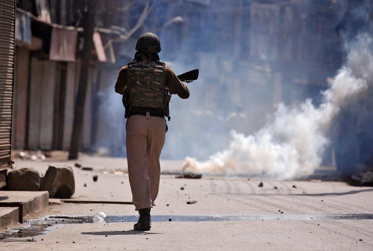 An policeman chases protesters amid tear gas smoke during a protest after Jumat-ul-Vida or the last Friday prayers of the holy fasting month of Ramadan, in Srinagar. (Reuters file photo)