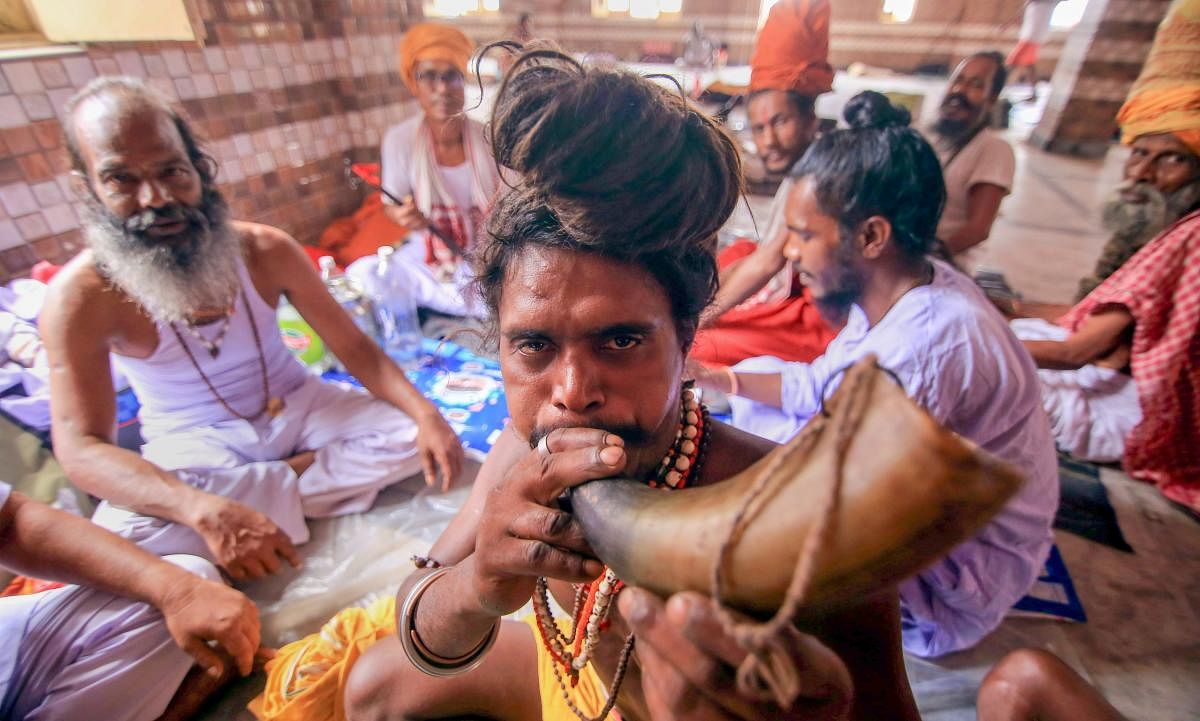 A Sadhu blows a buffalo-horn as they wait to register for the Amarnath Yatra, at Ram Mandir Basecamp in Jammu. PTI