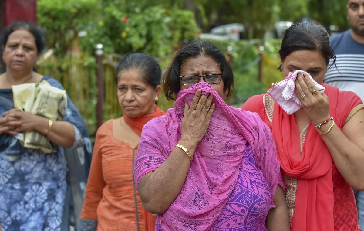 Relatives mourn during the cremation of 11 members of a family, who were found hanging in their house in Burari, at Nigambodh Ghat in New Delhi. (PTI Photo)