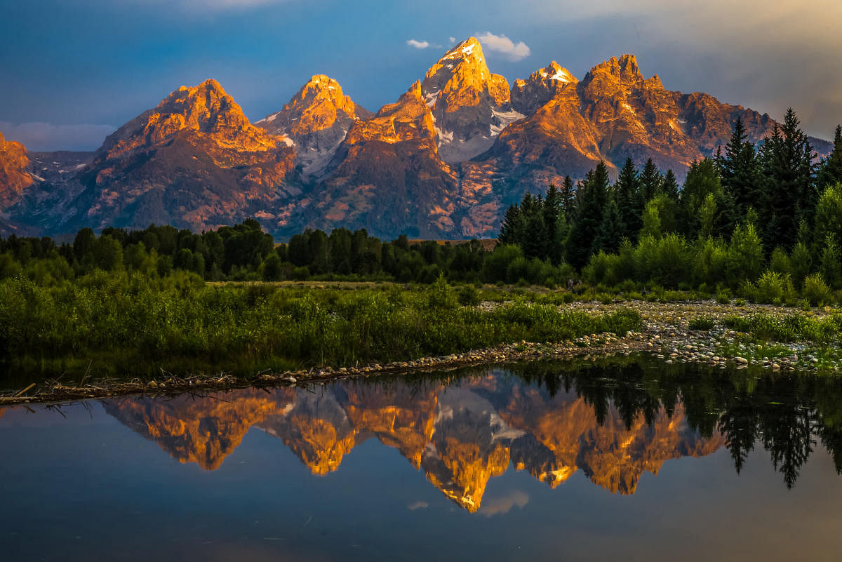 The dramatic colours of the Grand Teton Mountains reflecting in the water on a clear summer morning.