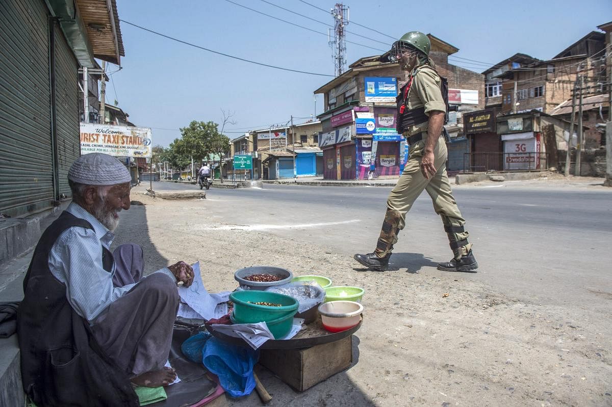 A security personal walks past a vendor during the second day of strike called by separatist leaders against the petitions filed in the Supreme court challenging the validity of Article 35A, in Srinagar. (PTI file photo)