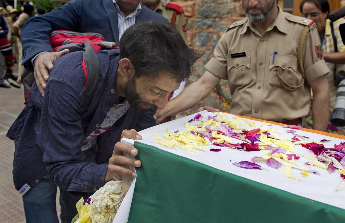 Brother of slain SG Constable Parvaiz Ahmad cries as he lays a wreath on the latter's coffin during a wreath-laying ceremony at District Police Lines, in Srinagar, on Sunday. PTI