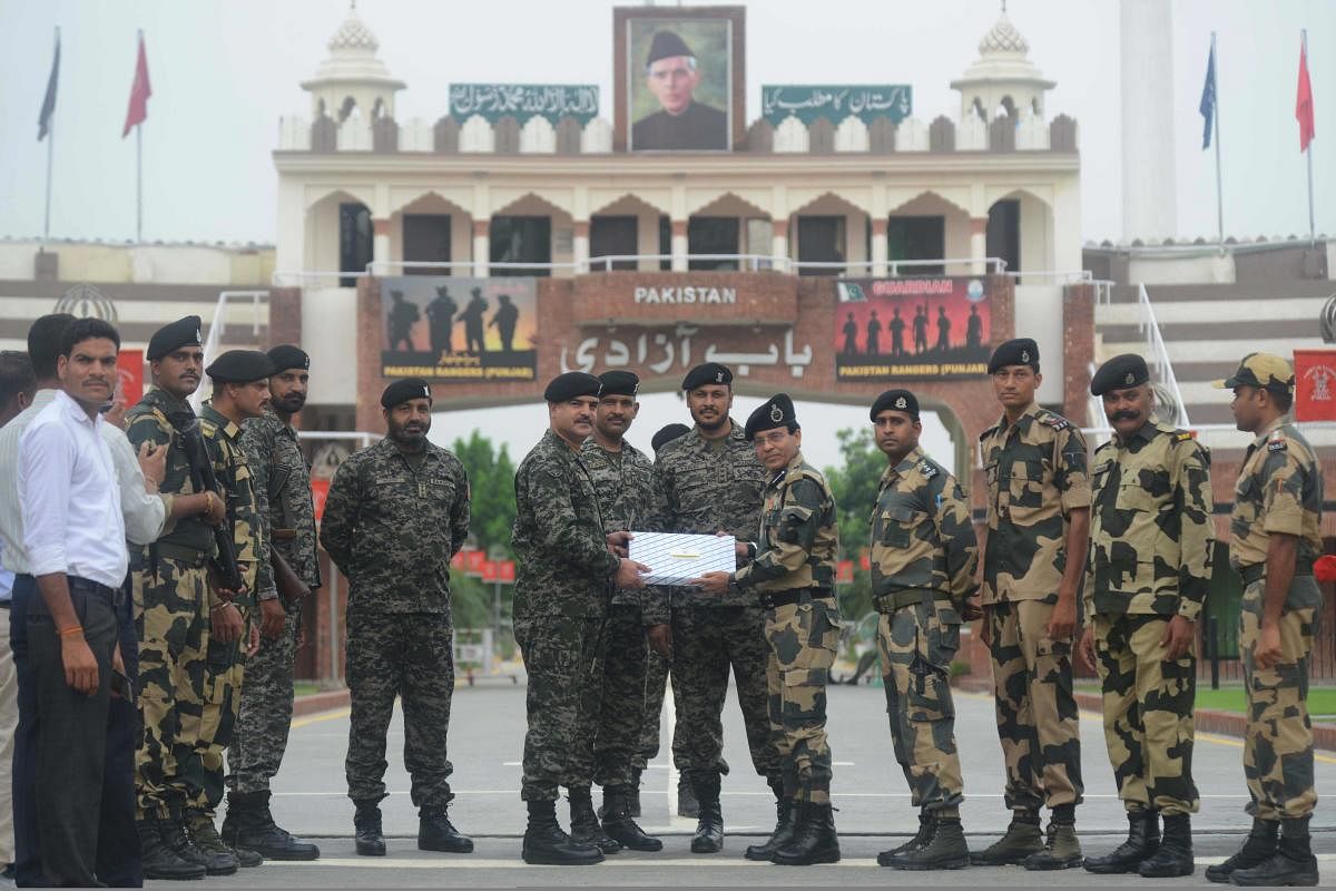 Pakistani Wing Commander Bilal (6L) presents sweets to Indian Border Security Force (BSF) Commandant Sudeep (5R) on the occasion of Eid al-Adha at the India-Pakistan Wagah border post on August 22, 2018. - AFP