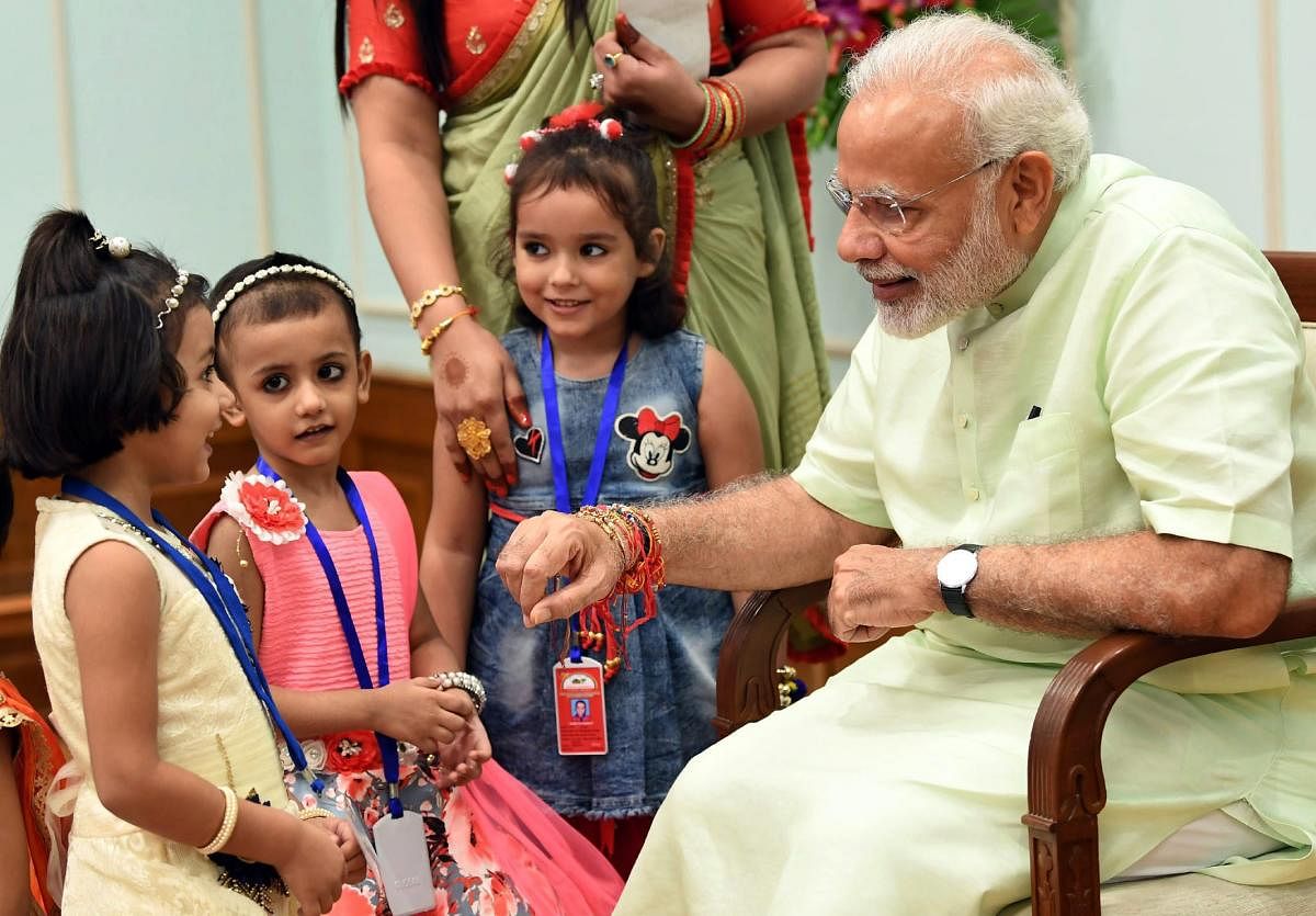 Children ties rakhi on Prime Minister Narendra Modi on the occasion of Raksha Bandhan festival, in New Delhi on Sunday, Aug 26, 2018. (PIB Photo via PTI)