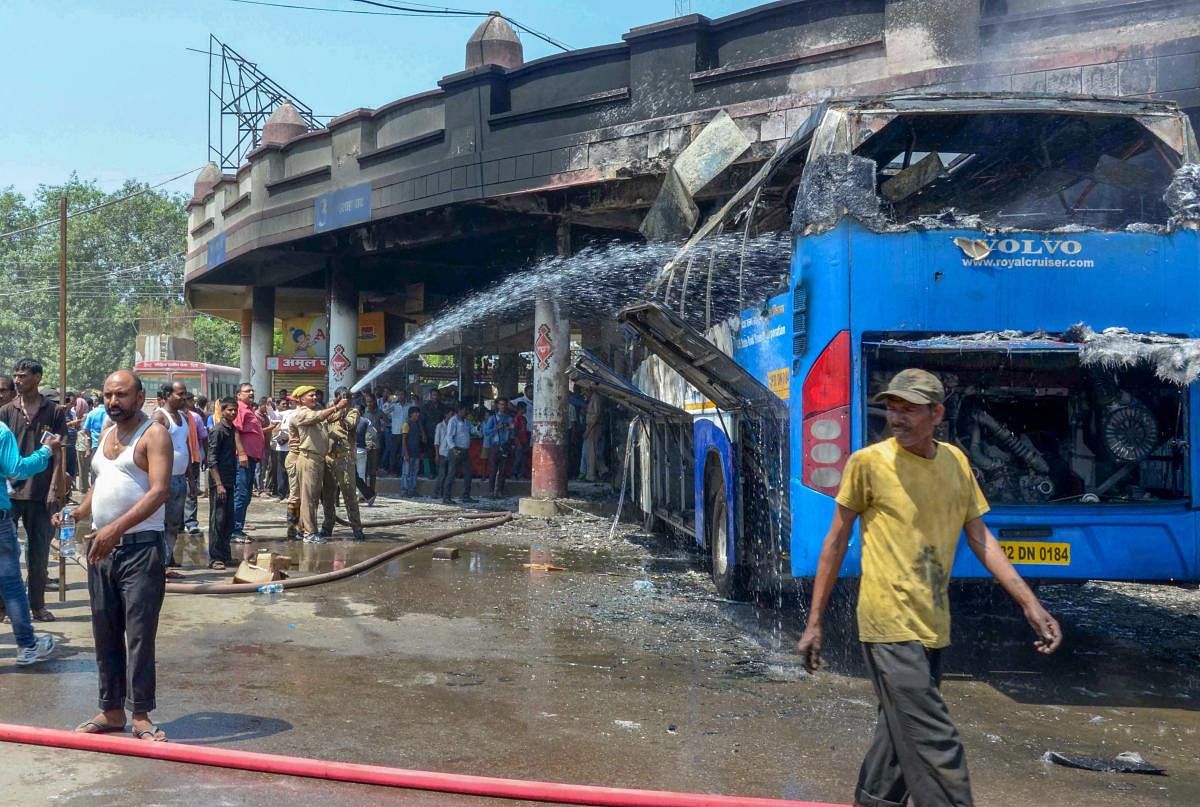 Firefighters douse a fire at a roadways bus that was reportedly torched by a woman protester during a protest for the separate state of 'Purvanchal', in Varanasi on Wednesday. PTI