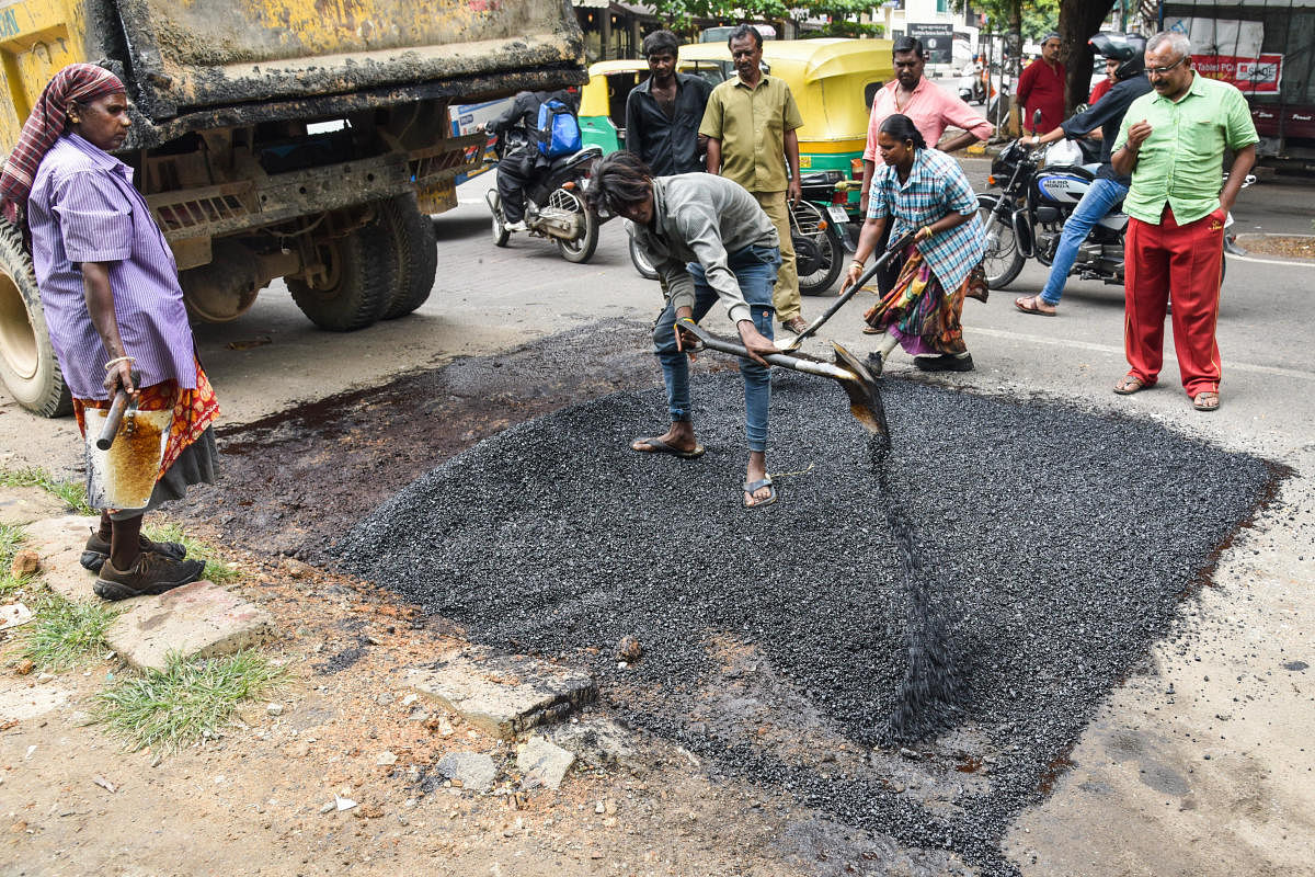 BBMP workers filling the potholes in Jayanagar 4T Block on Friday. DH photo/S K Dinesh